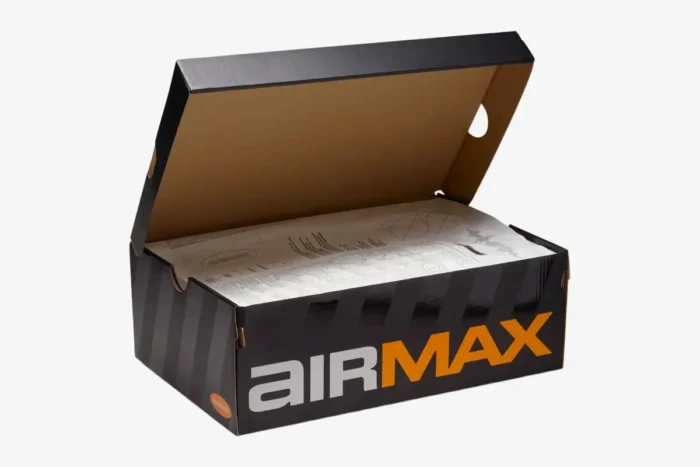 Three-quarter view of an open black and orange Nike Air Max DN8 shoebox with graphic tissue paper. - SKU  FQ7860-100