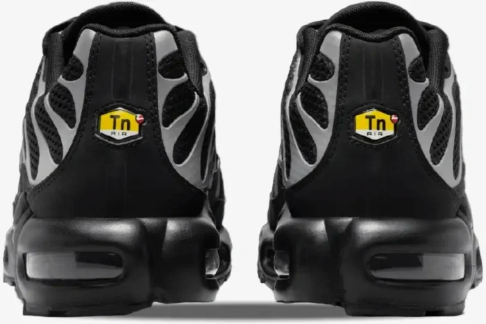 Rear view of Nike Air Max Plus sneakers in black and reflective silver with yellow Tn Air heel logos. - SKU HQ3029-001