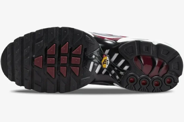 Outsole view of Nike Air Max Plus in red, grey, and white, featuring black rubber with burgundy accents. - SKU DQ3983-600