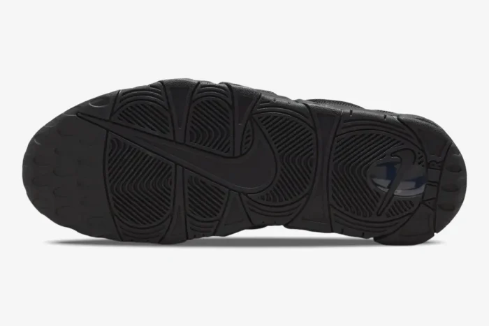 Outsole view of the Nike Air More Uptempo Low Triple Black sneaker showing the traction pattern and Nike swoosh. - SKU IM6649-001
