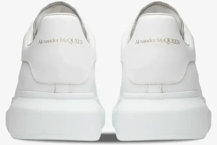 Rear view of white Alexander McQueen Oversized Sneakers showing the gold logo on the heel tab. - SKU 553680-WHGP5-9000