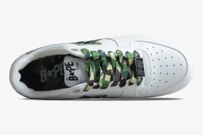 Top-down view of a white Bape Sta Low sneaker featuring green camo laces and branding. - SKU 1K70191335-GRN