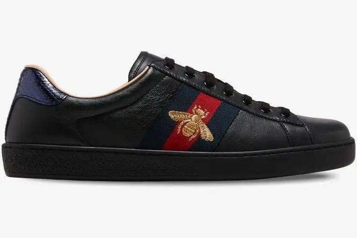 gucci-ace-bee-black-leather-sneaker-side-view-42944602jp01284-712-543 Side view of Gucci Ace Bee black leather sneakers with gold bee embroidery and web stripe. - SKU 42944602JP01284