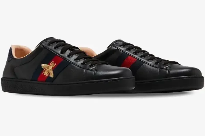 Side view of Gucci Ace Bee black leather sneakers with navy and red web stripe and gold bee. - SKU 42944602JP01284