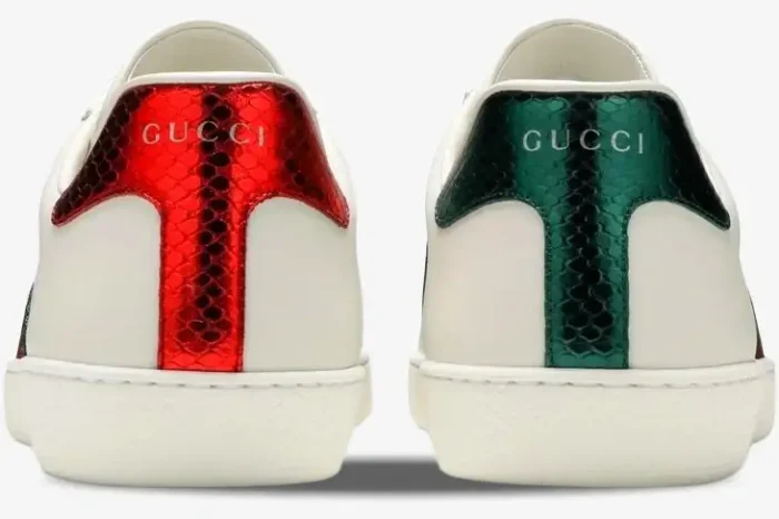 Back view of Gucci Ace white leather sneakers with mismatched metallic red and green snakeskin heel tabs. - SKU 42944602JP09064