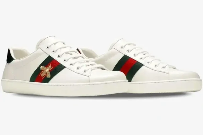 Pair of white leather Gucci Ace sneakers with gold bee embroidery and green-red stripes, side view. - SKU 42944602JP09064