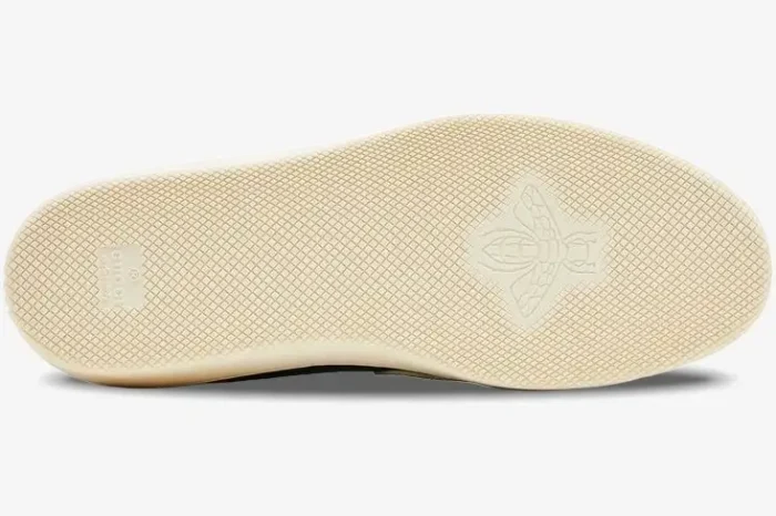 Bottom view of the cream rubber sole of a Gucci G74 sneaker featuring an embossed bee logo. - SKU 791742AADM03143