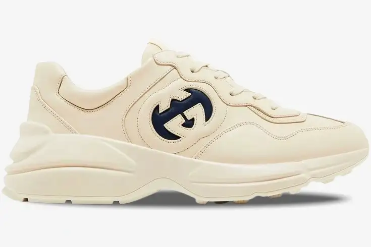 gucci-rhyton-interlocking-g-ivory-blue-side-757857upg709567-702-199 Side view of a Gucci Rhyton sneaker in ivory leather featuring a navy blue interlocking G logo. - SKU 757857UPG709567