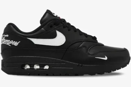 Side view of Nike Air Max 1 '87 SP x Supreme black leather sneakers with white swoosh and 'Famous' heel script. - SKU HF8813-001