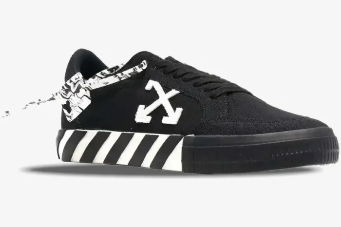 Side view of Off-White Low Vulcanized black sneakers with white arrow logo and striped midsole. - SKU OWIA272C99LEA0011001