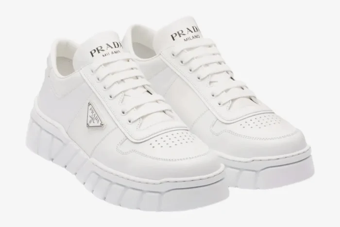Pair of white Prada low top sneakers with geometric tread shown from a three-quarter front angle. - SKU 2EE3783LJ6F0009