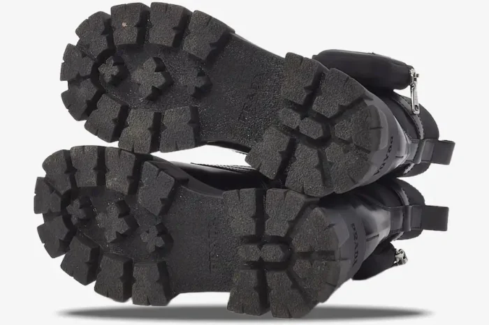 Bottom view of black Prada Monolith leather boots showing chunky lug soles and brand logo. - SKU 1T255M_3L09_F0002_F_055